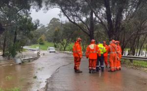 VICSES volunteers in orange standing next to floodwater and a vehicle that has entered floodwater